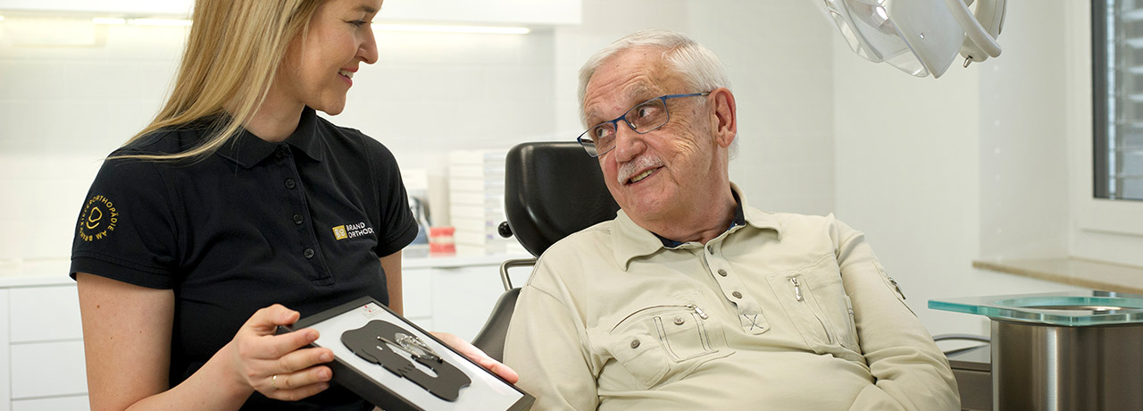 Kieferorthopäde Desislava Stanchev erklärt einem älteren Herrn das Kiefergelenk | Brand Orthodontics Mainz